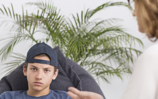 Angry boy sitting with therapist
